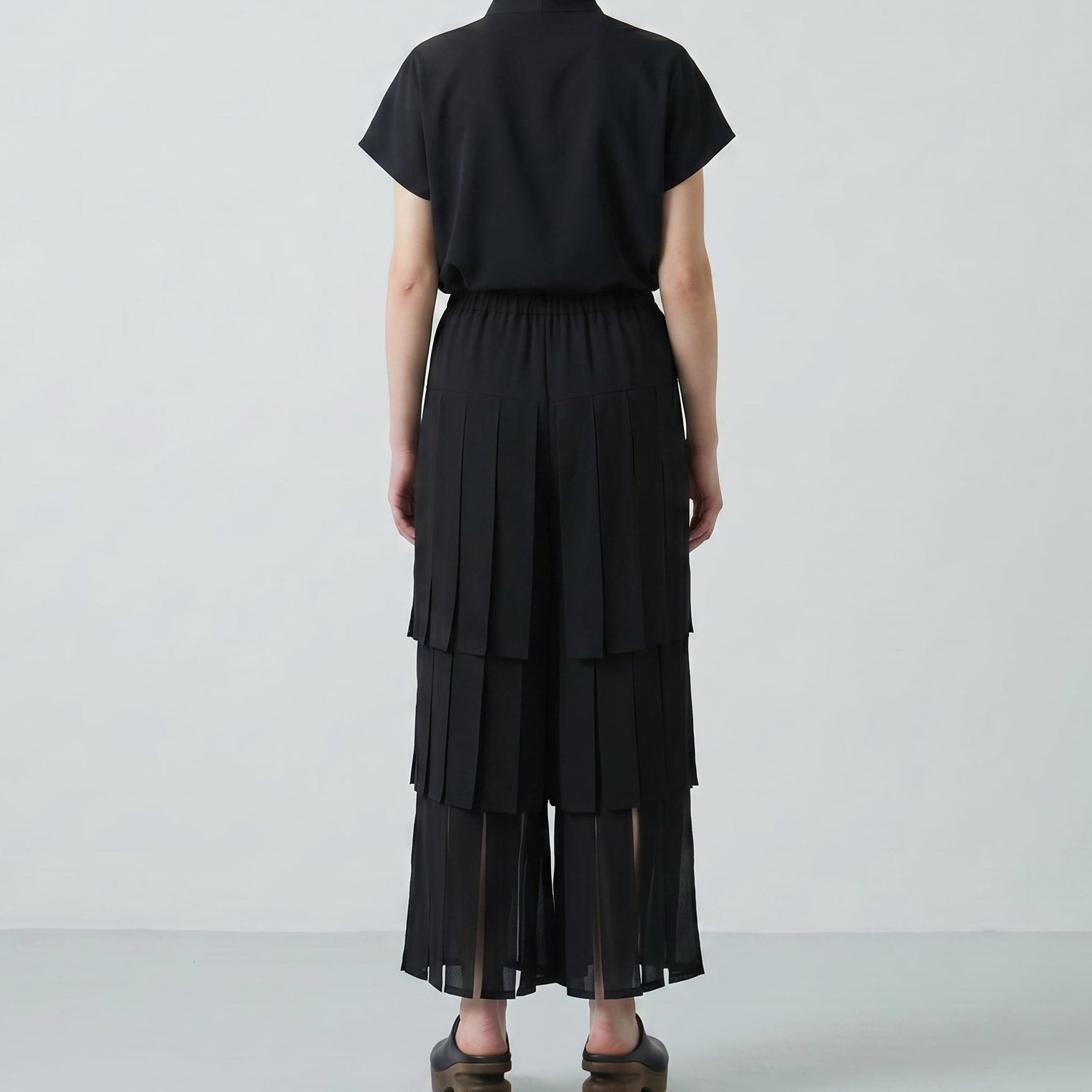 Person wearing a black outfit with layered skirt on a white background